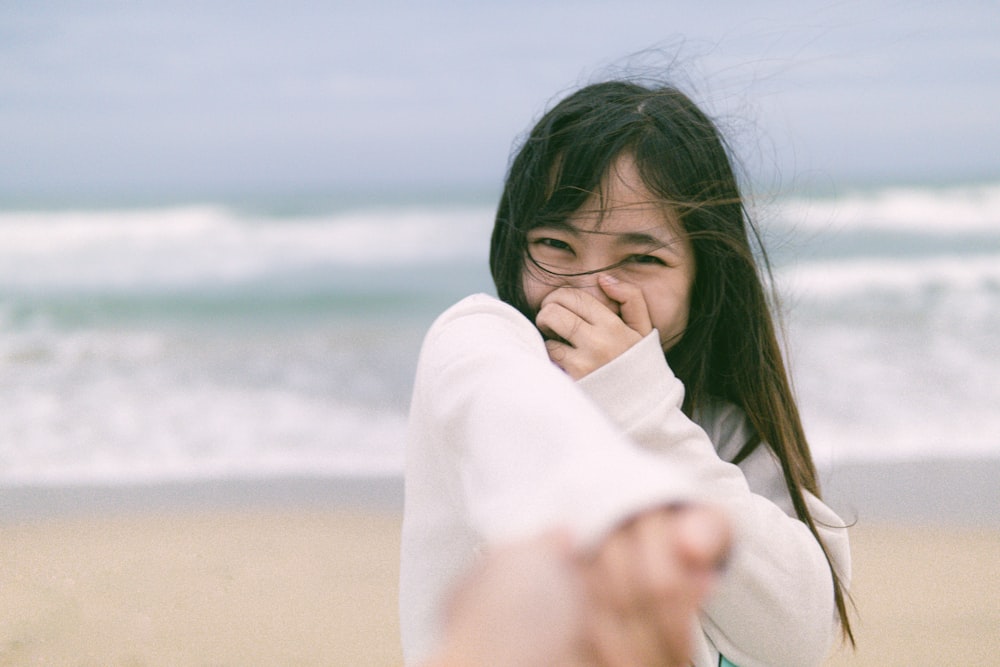 woman in white long sleeve shirt standing on beach during daytime