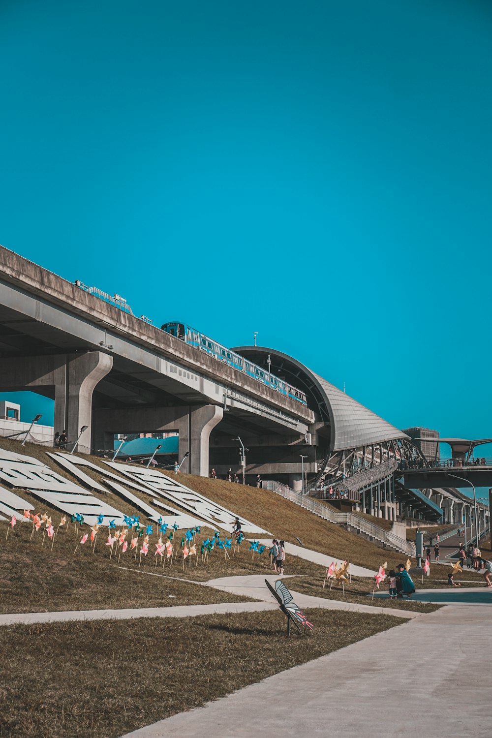 personnes marchant sur un pont en béton gris sous un ciel bleu pendant la journée