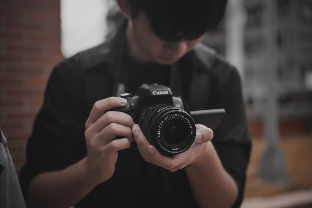 Hombre con camisa negra sosteniendo una cámara DSLR Nikon negra