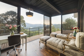 A bright, modern living room with large windows overlooking pine trees.