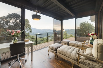 A bright, modern living room with large windows overlooking pine trees.