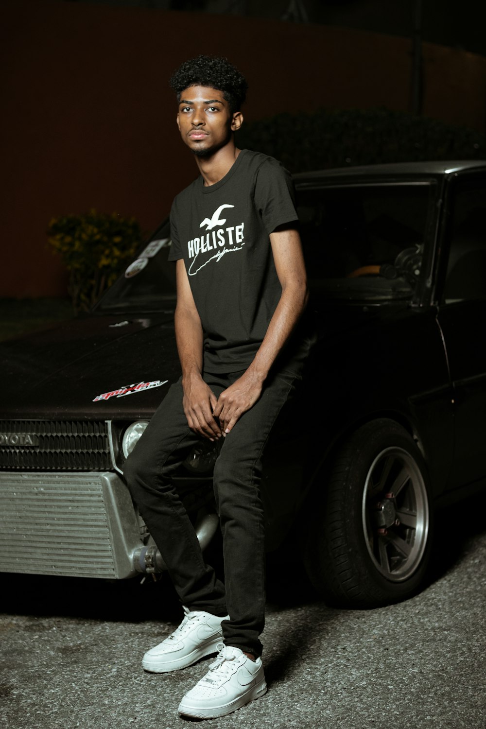 man in black crew neck t-shirt and black pants sitting on black car