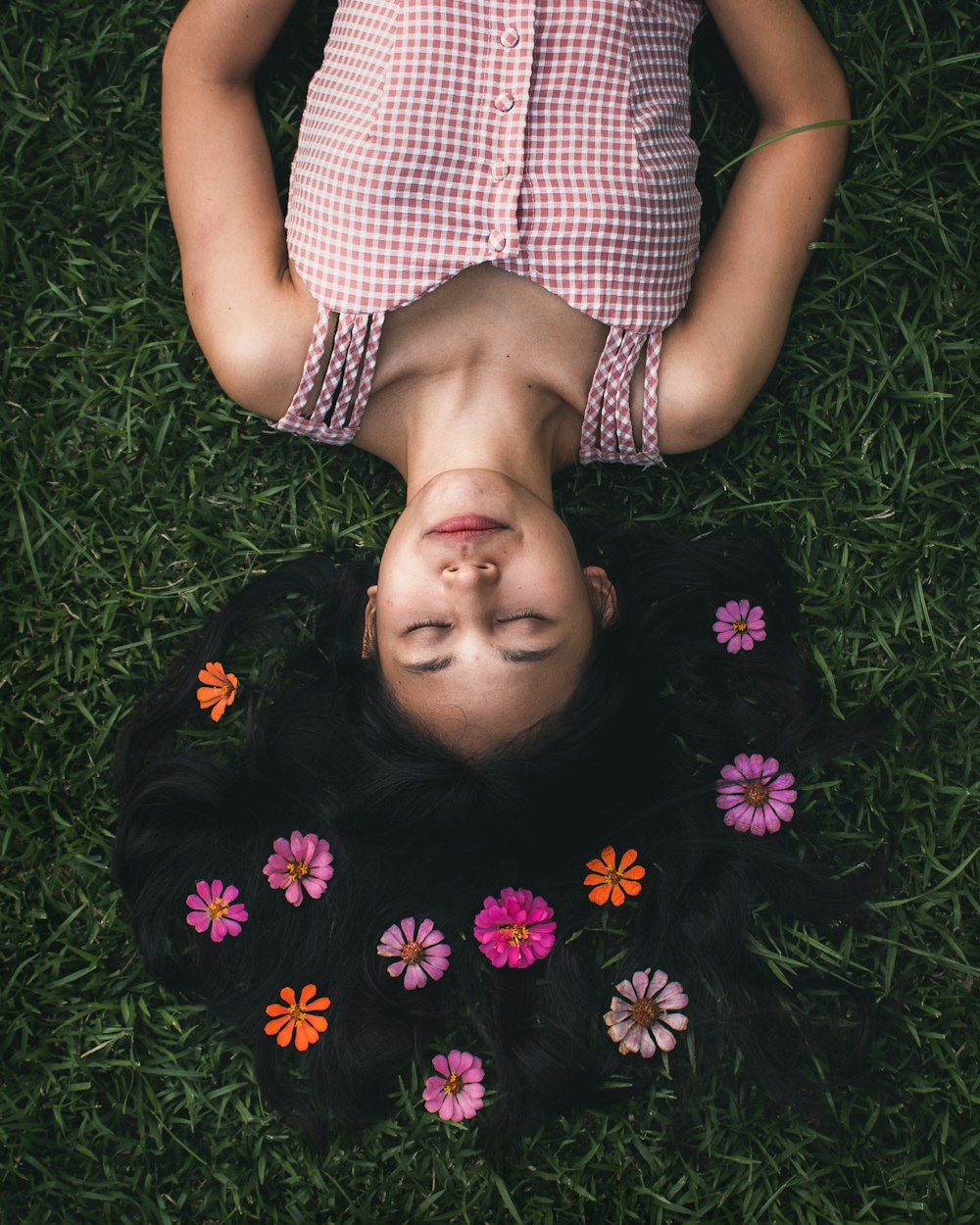 woman in black and white polka dot dress lying on green grass field