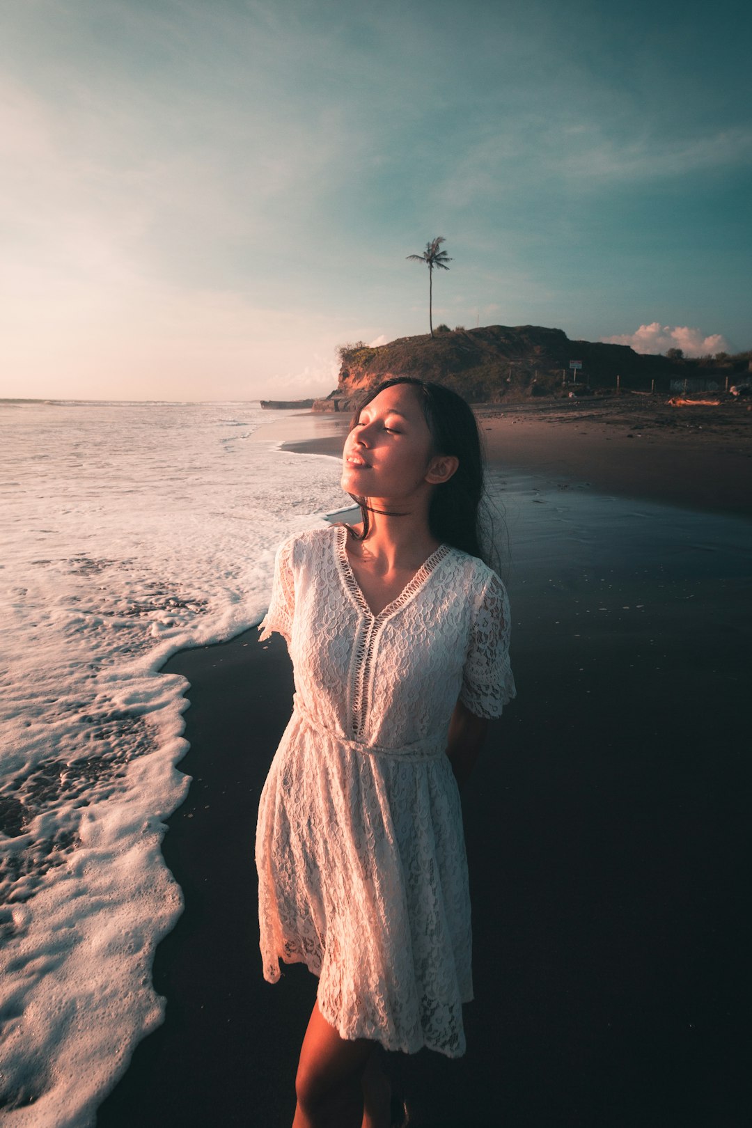 woman in white dress standing on seashore during daytime