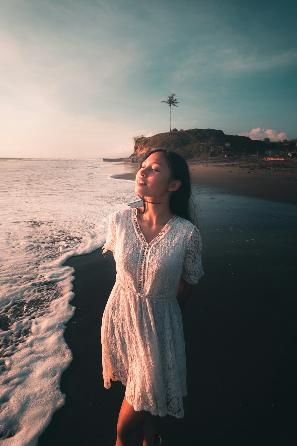 mulher no vestido branco que está na costa durante o dia