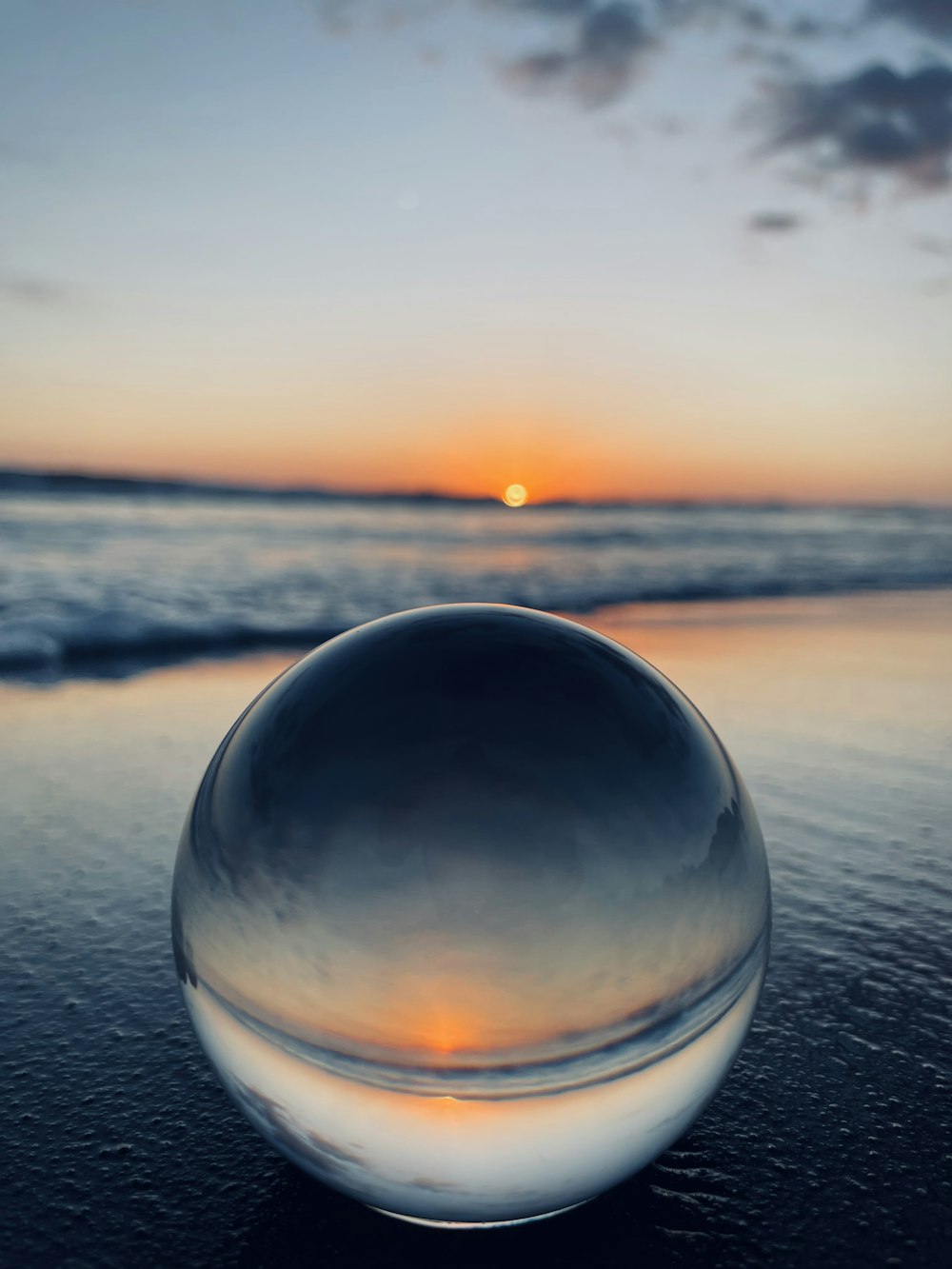 clear glass ball on black sand during sunset