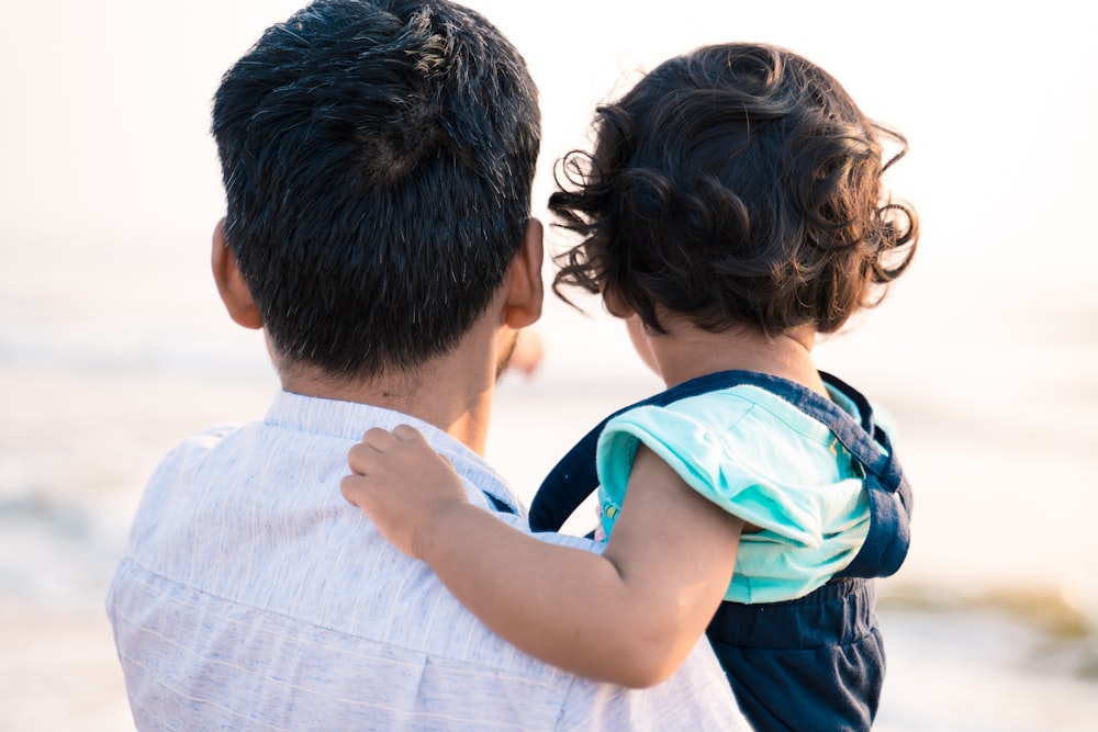 man in blue and white shirt carrying boy in blue and white shirt during daytime