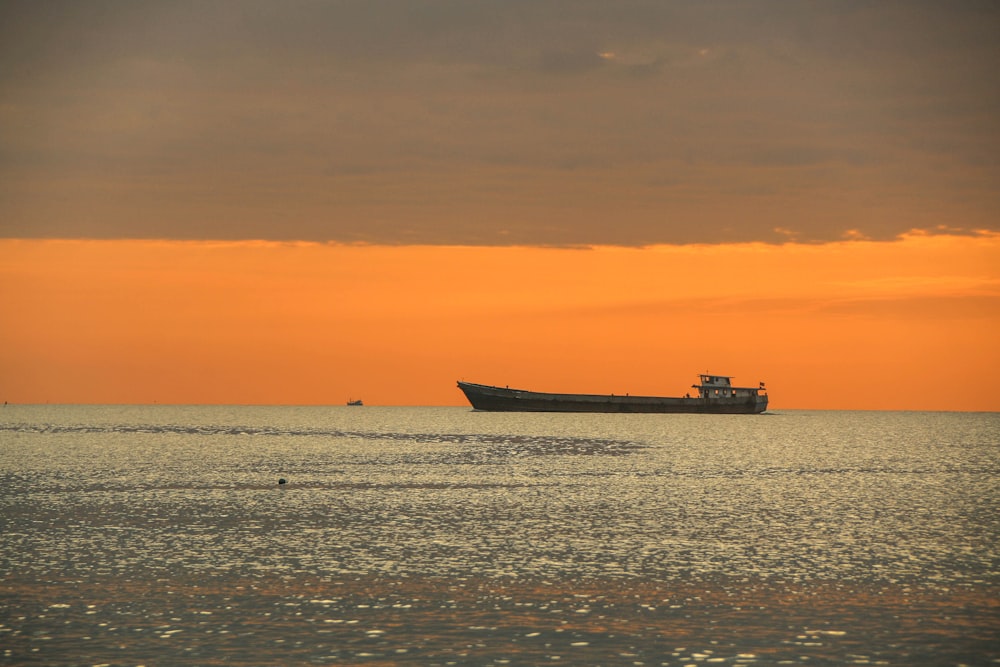 black ship on sea during sunset