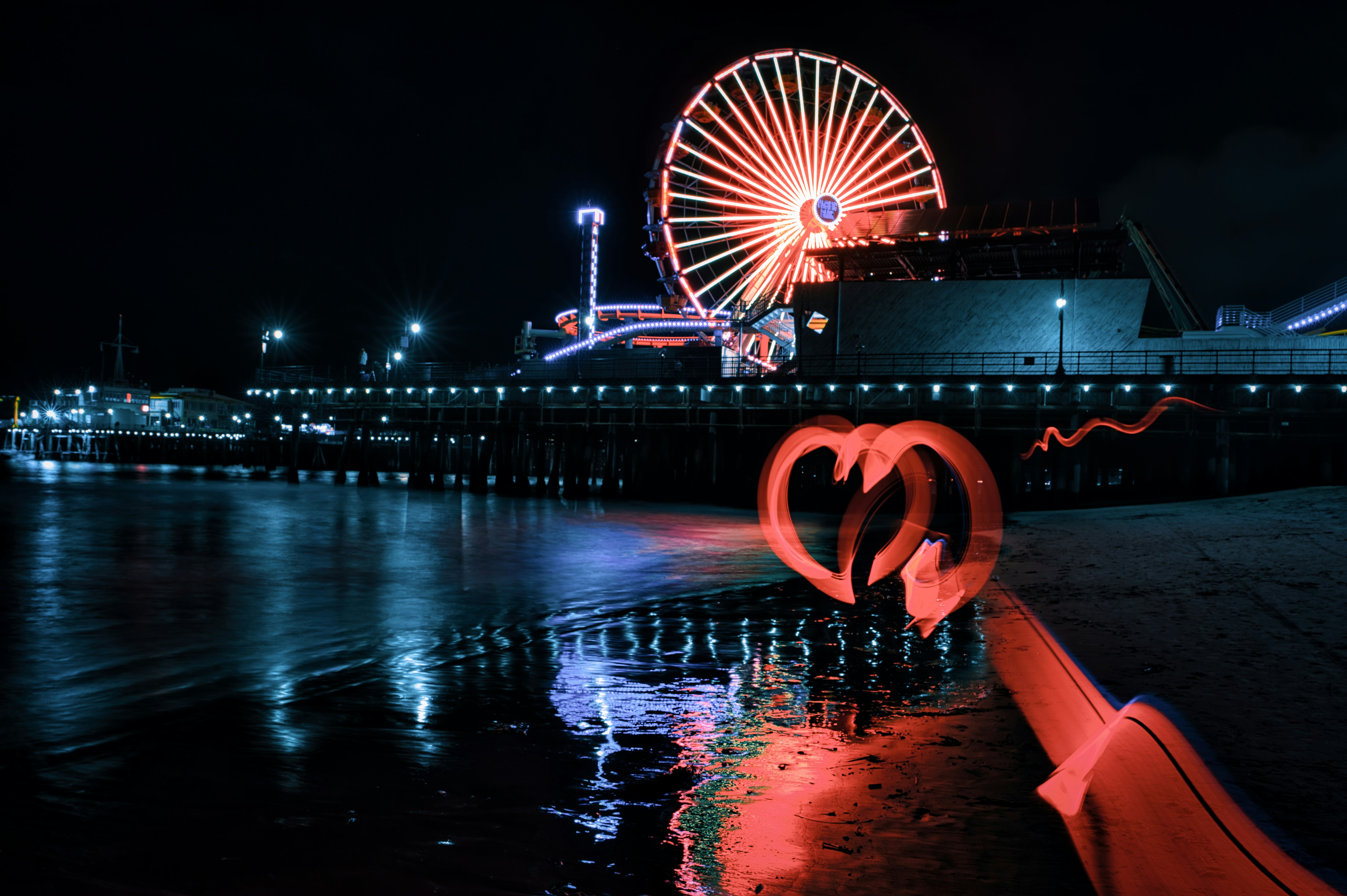 red and white ferris wheel near body of water during night time