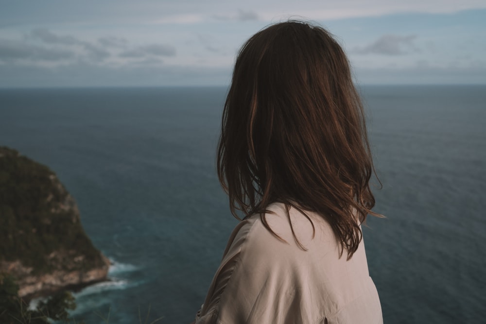 woman in white shirt looking at the sea during daytime