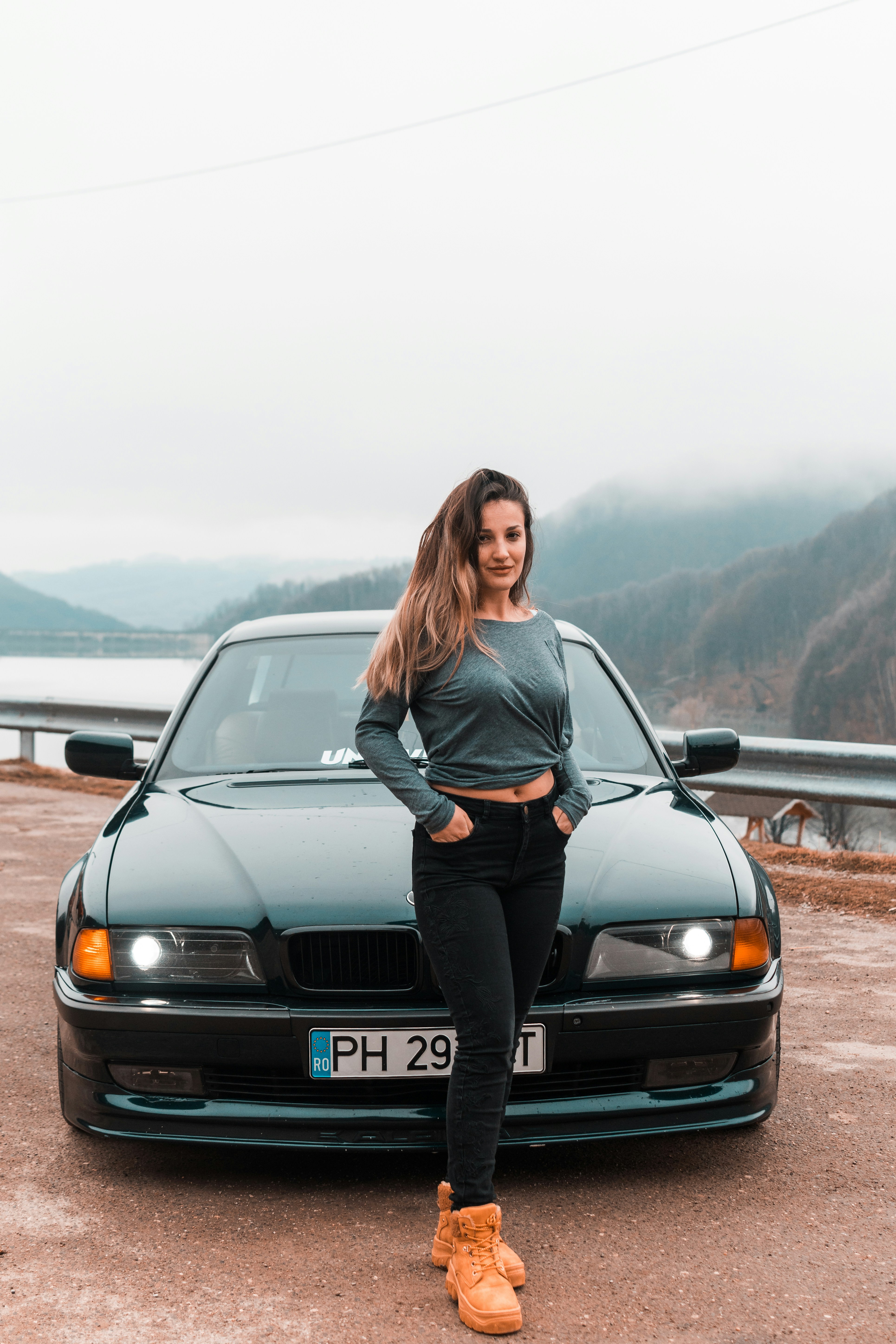woman in gray long sleeve shirt and black pants standing beside black car