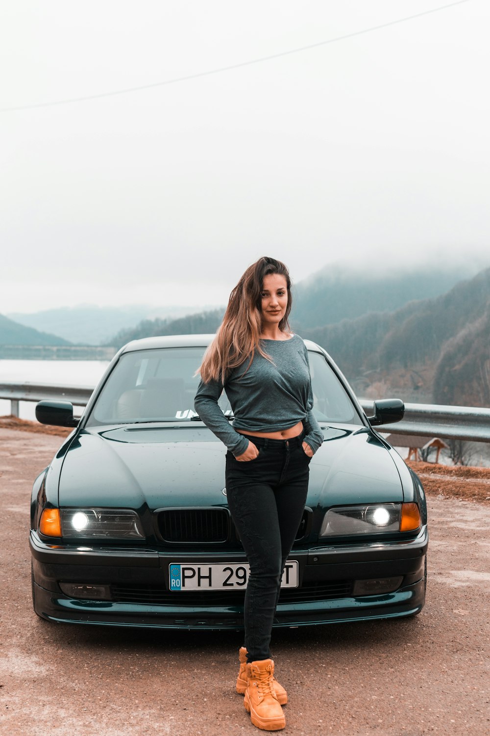 woman in gray long sleeve shirt and black pants standing beside black car