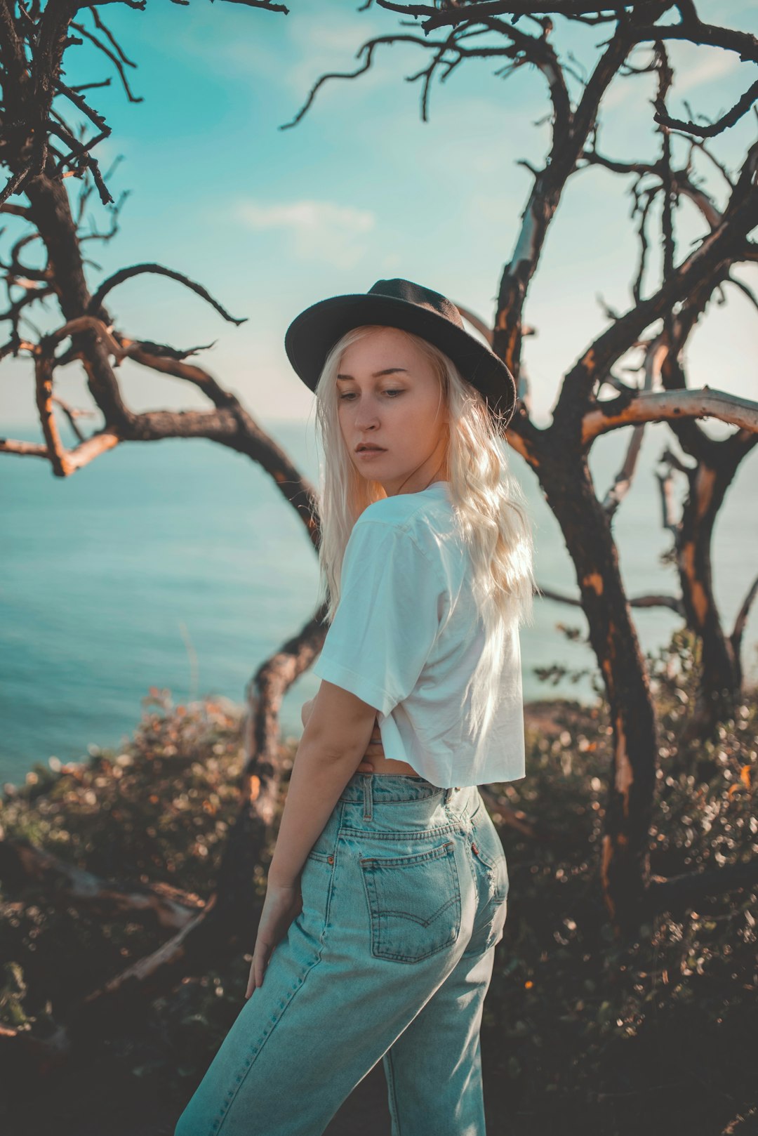 woman in white crew neck t-shirt and blue denim shorts standing near brown tree during