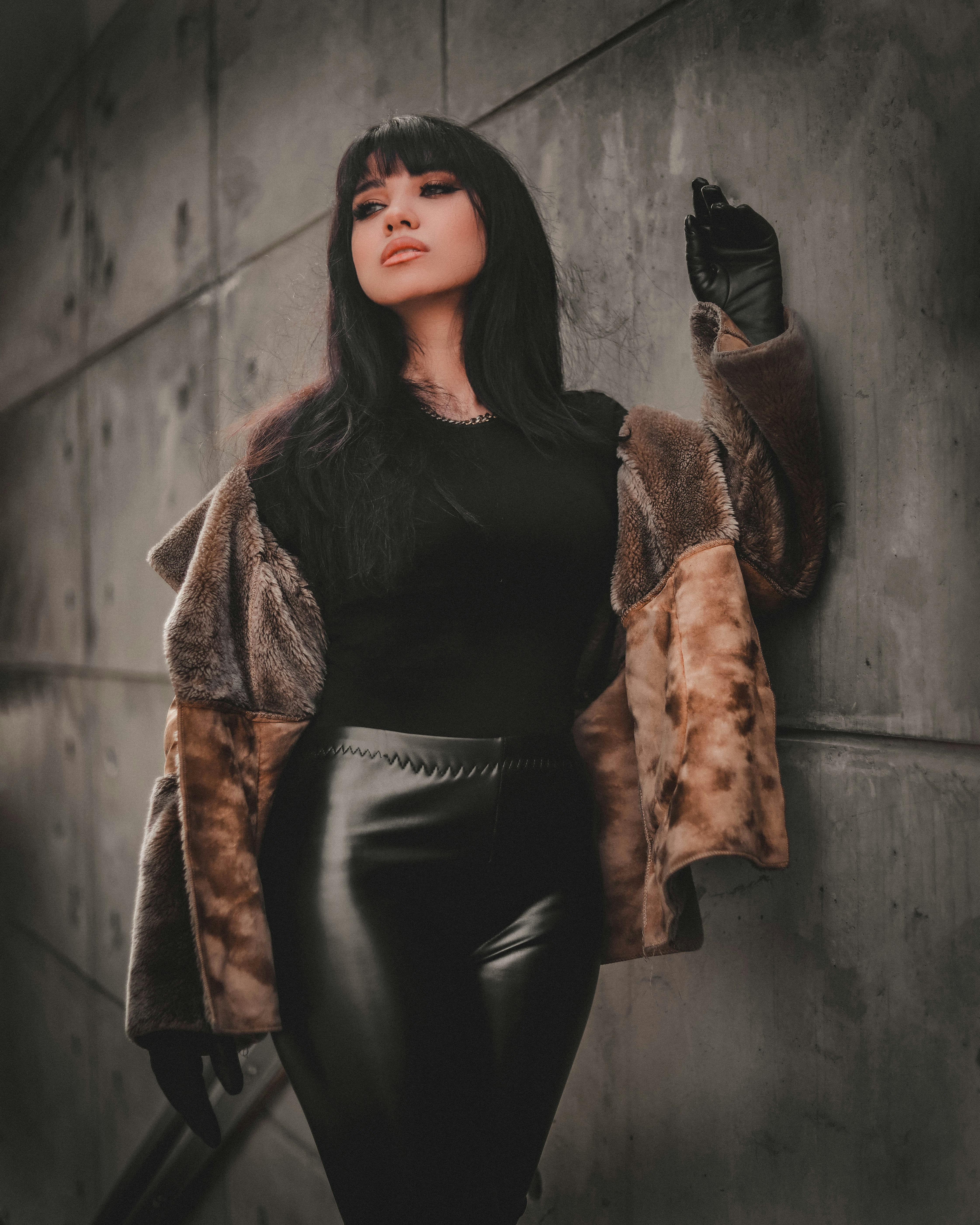 wanita dengan jaket kulit hitam dan celana hitam bersandar di dinding