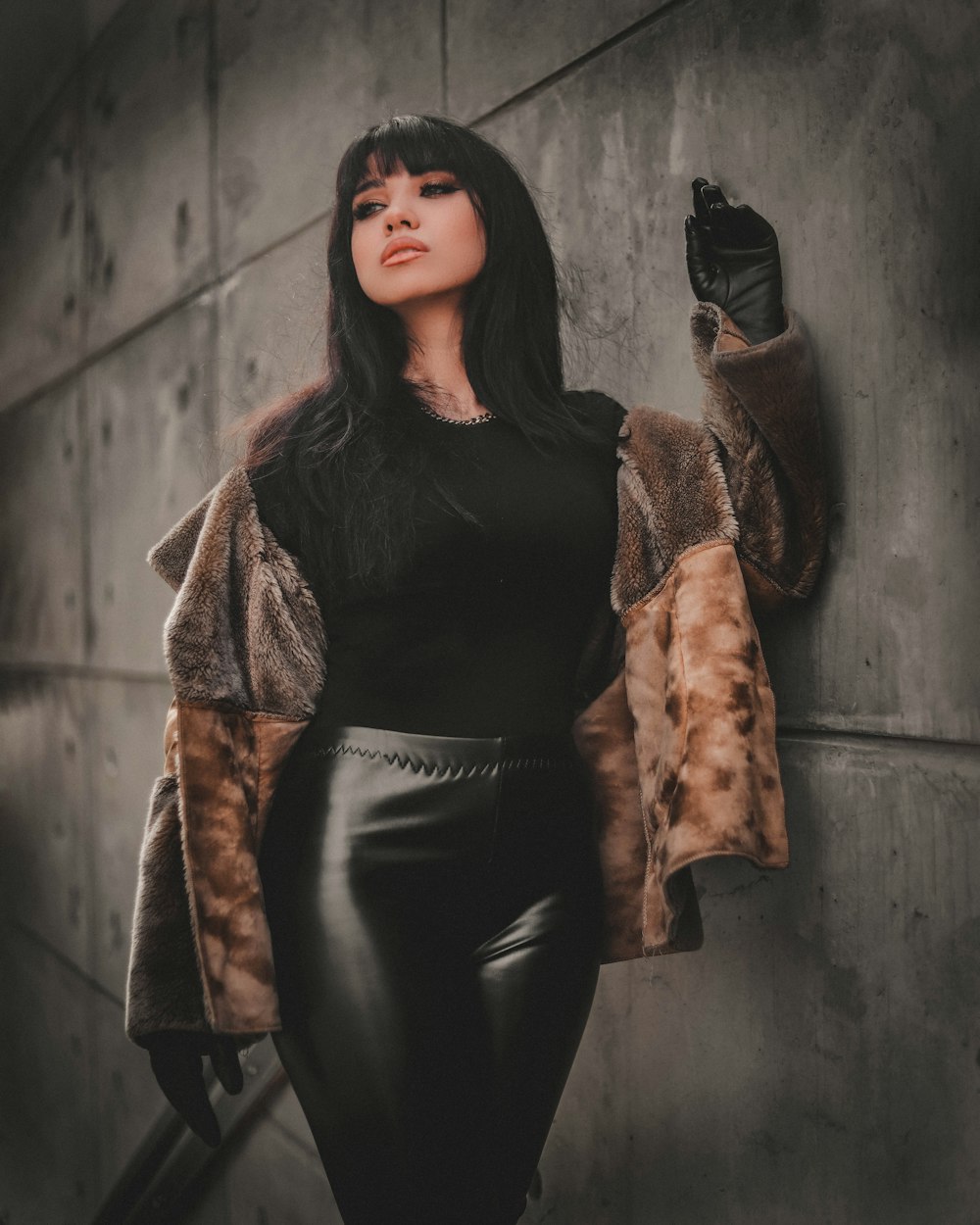 woman in black leather jacket and black pants leaning on wall