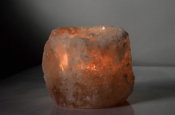 Soft glowing Himalayan salt lamp casting warm light on a rustic wooden table.