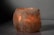 A glowing Himalayan salt lamp with a rough, textured surface emits a warm, amber light. The lamp sits on a smooth, neutral-colored surface against a plain background, creating a calming and serene atmosphere.