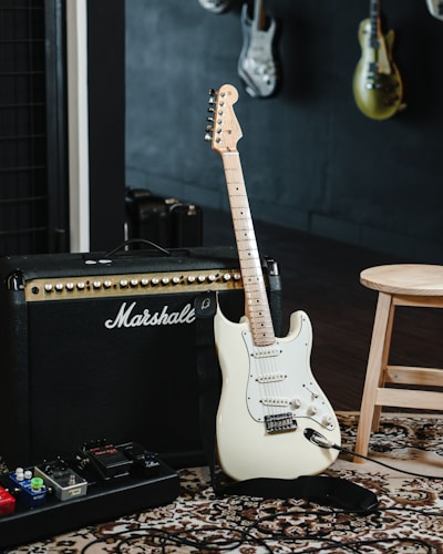 white and black stratocaster electric guitar on black guitar amplifier