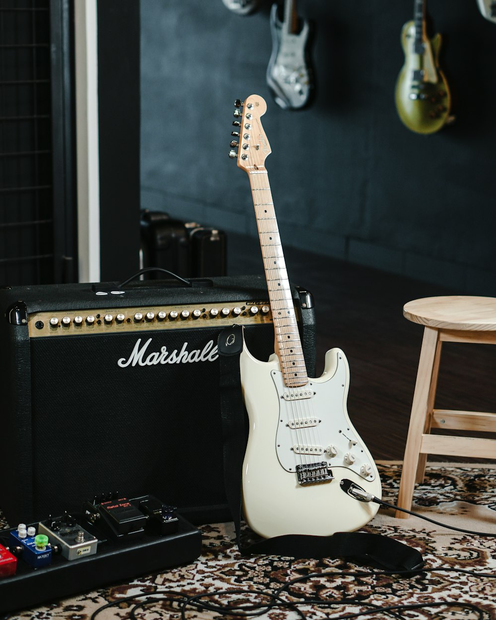 Guitarra eléctrica Stratocaster blanca y negra sobre amplificador de guitarra negro