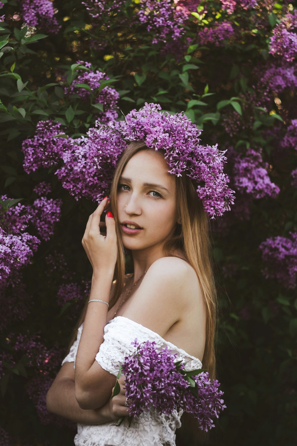 woman in white floral off shoulder dress holding her face