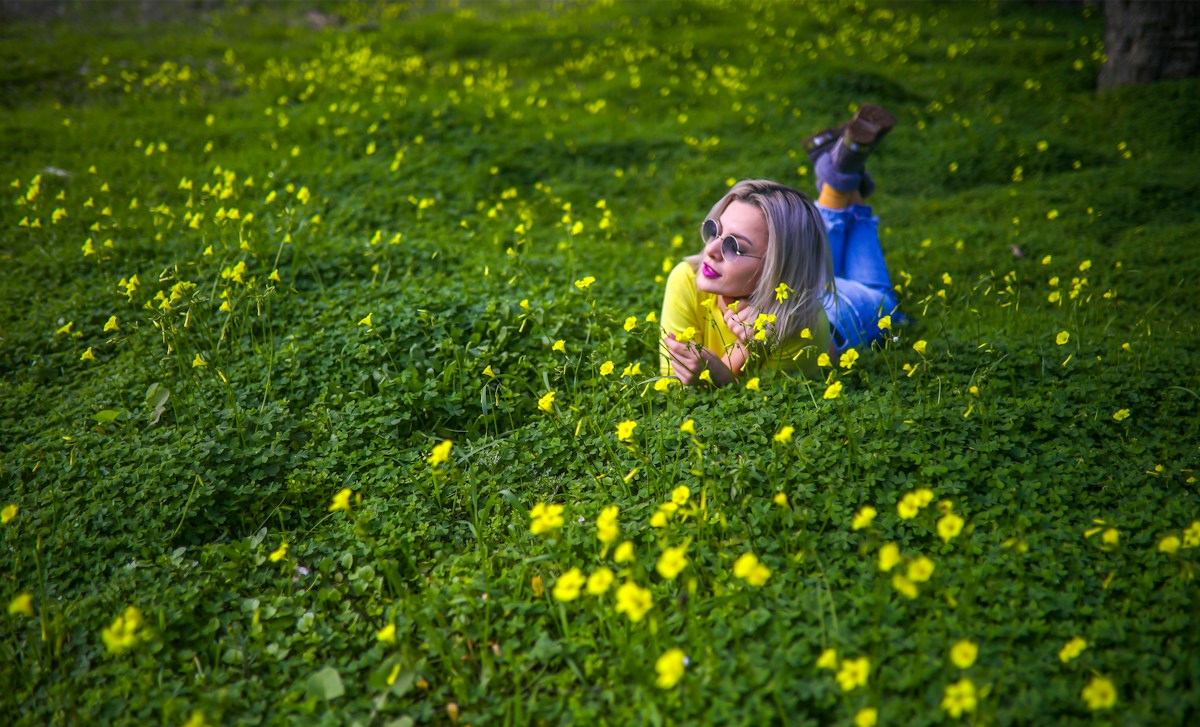 Girl in yellow jacket searching for Easter eggs in a flower-filled field during daytime