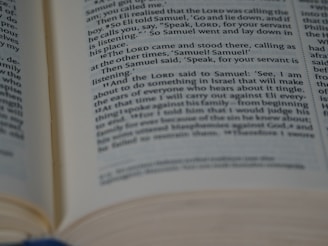 An open book with legible text in English, likely a religious or biblical passage due to the mention of names like Samuel and LORD. The focus is on the text, with the pages slightly curved and bound together.