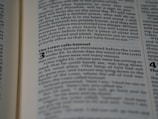An open book displaying text in a serif font on light-colored pages. The visible text includes a heading and several lines of body text, with certain words emphasized in bold.