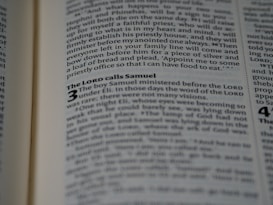 An open book displaying text in a serif font on light-colored pages. The visible text includes a heading and several lines of body text, with certain words emphasized in bold.