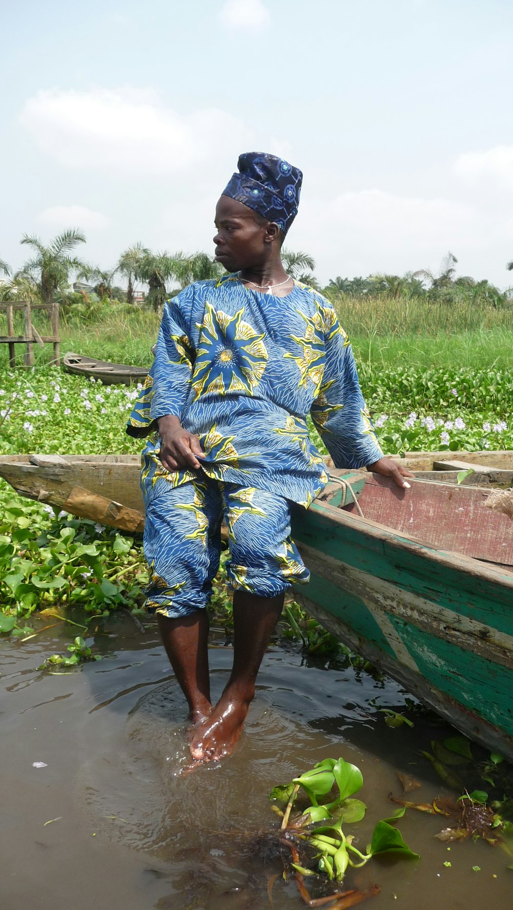 woman in blue and white floral dress sitting on brown wooden boat during daytime