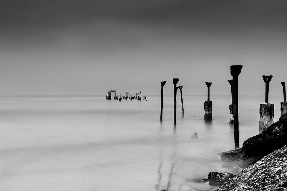 grayscale photo of dock on body of water