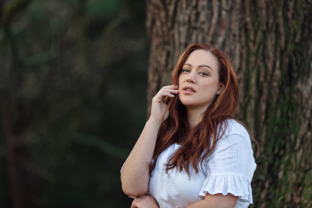 woman in white shirt leaning on brown tree