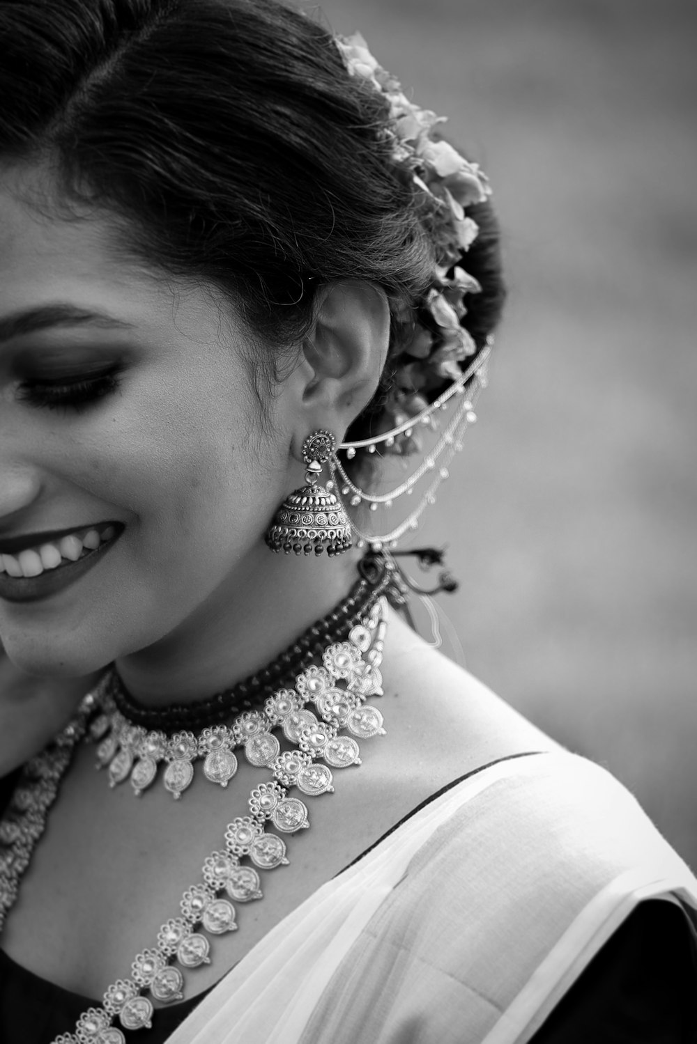 grayscale photo of smiling woman wearing silver necklace