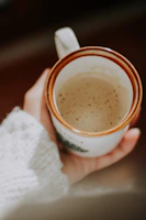 Close-up of a white ceramic mug with a vibrant custom print sitting next to a cozy sweater.