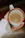 A close-up of a hand holding a bright blue hand-thrown ceramic mug with a cozy knitted sweater in the background.