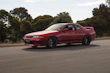 A shiny red sports car speeding along a coastal highway, with motion blur capturing its speed.