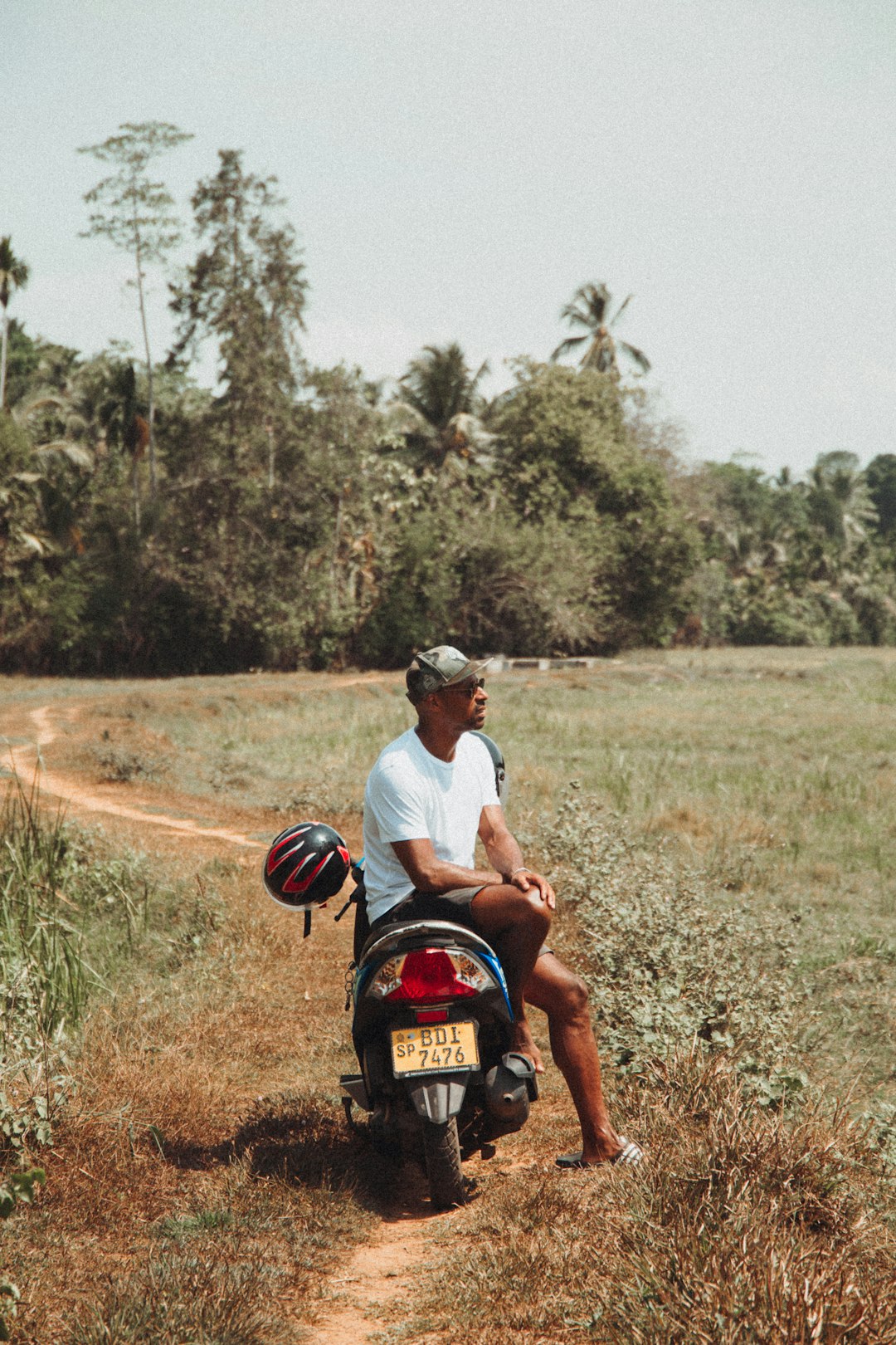 man in white t-shirt riding on red motorcycle during daytime