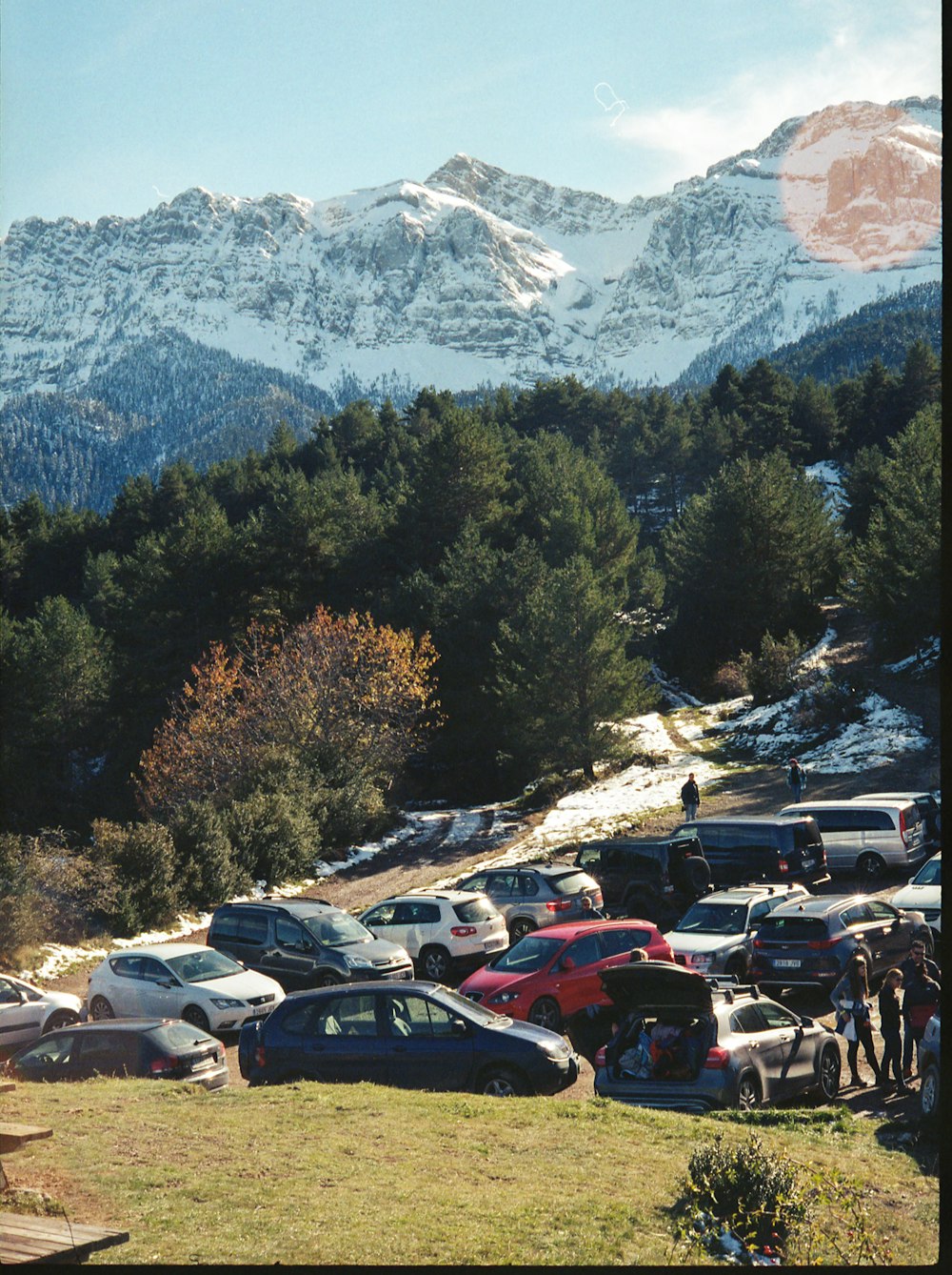 cars parked on parking lot near trees and mountains during daytime
