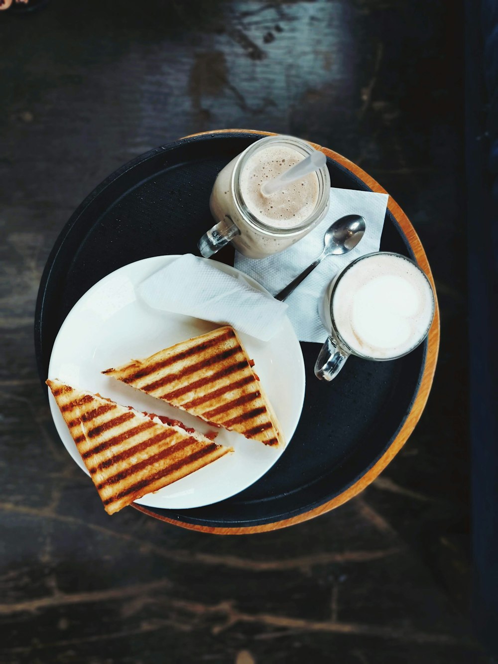 a plate topped with a cut in half sandwich next to a cup of coffee
