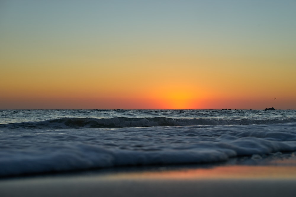 ocean waves crashing on shore during sunset