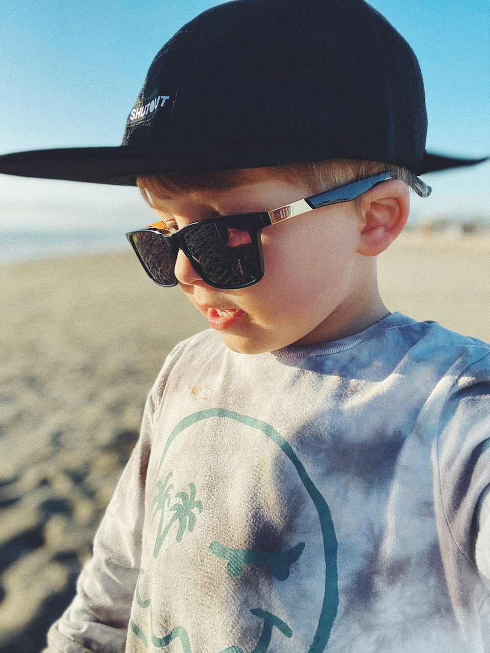 boy in white and green crew neck shirt wearing black sunglasses and black cap