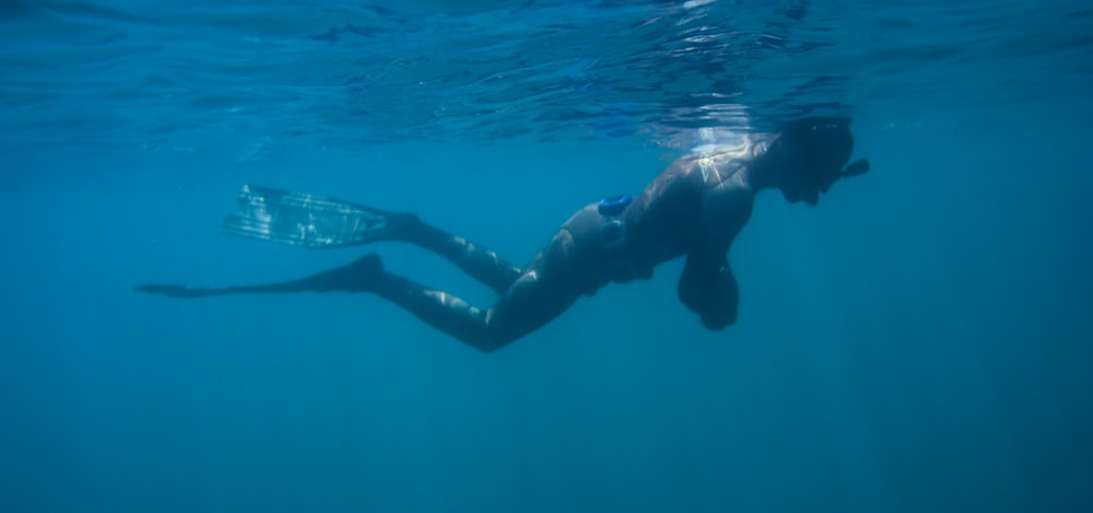 hombre en pantalones cortos negros nadando en el agua