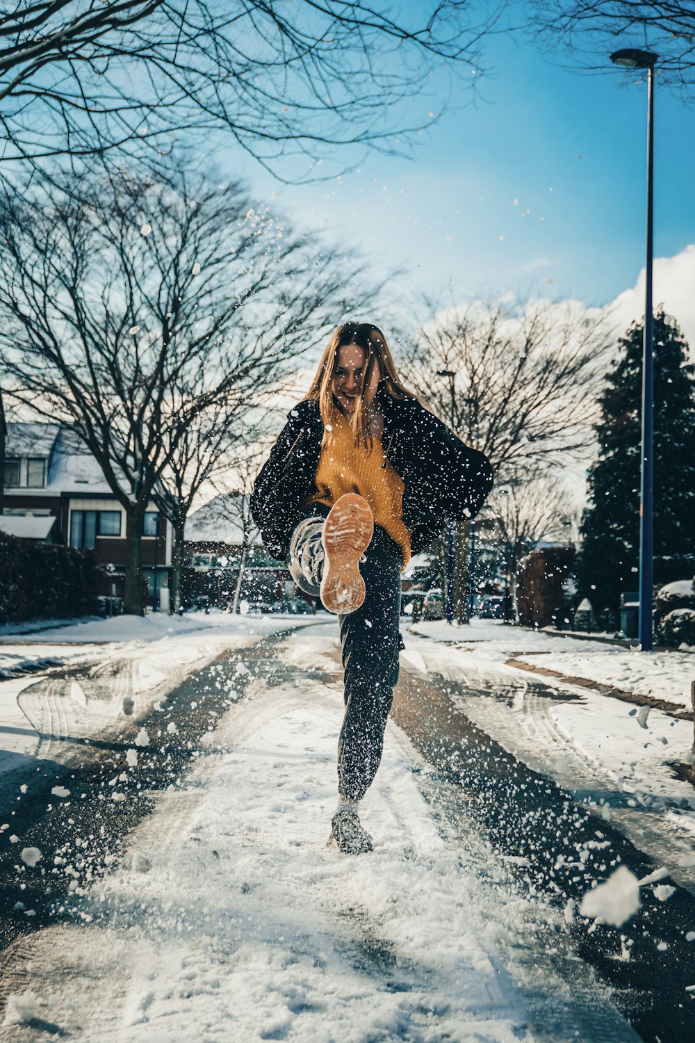 Mujer con chaqueta negra de pie en el suelo cubierto de nieve durante el día