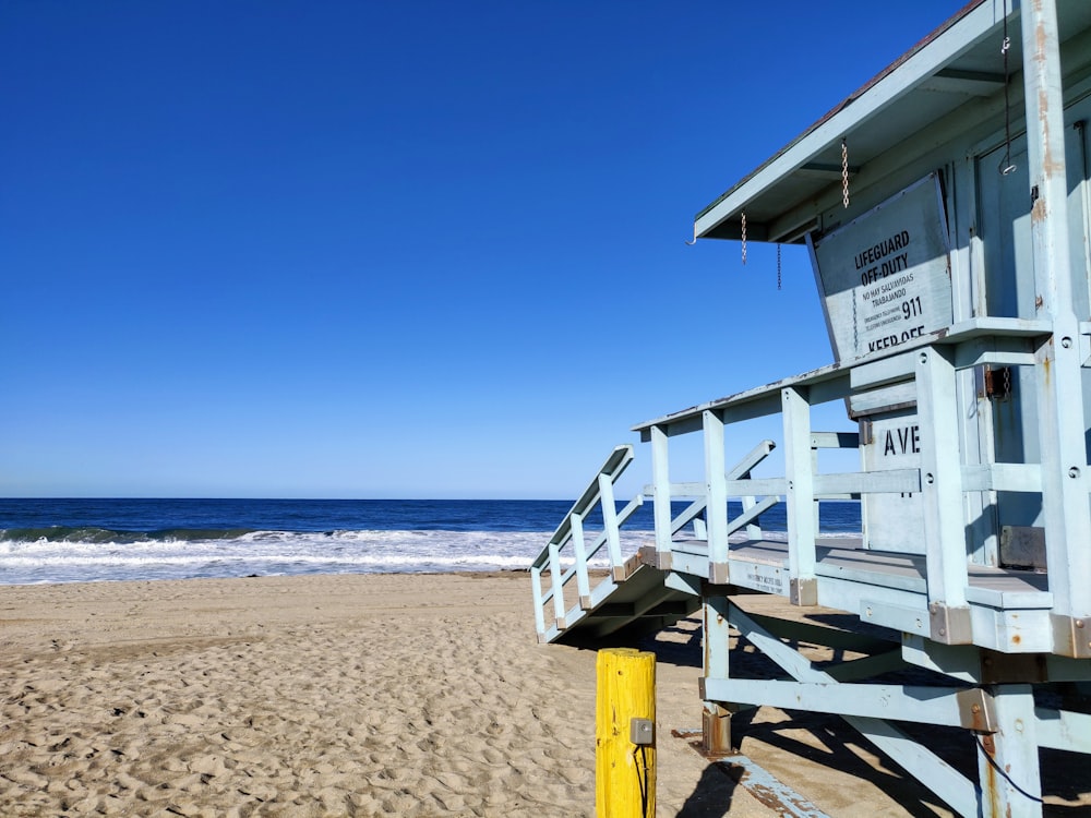 white wooden lifeguard house on beach during daytime