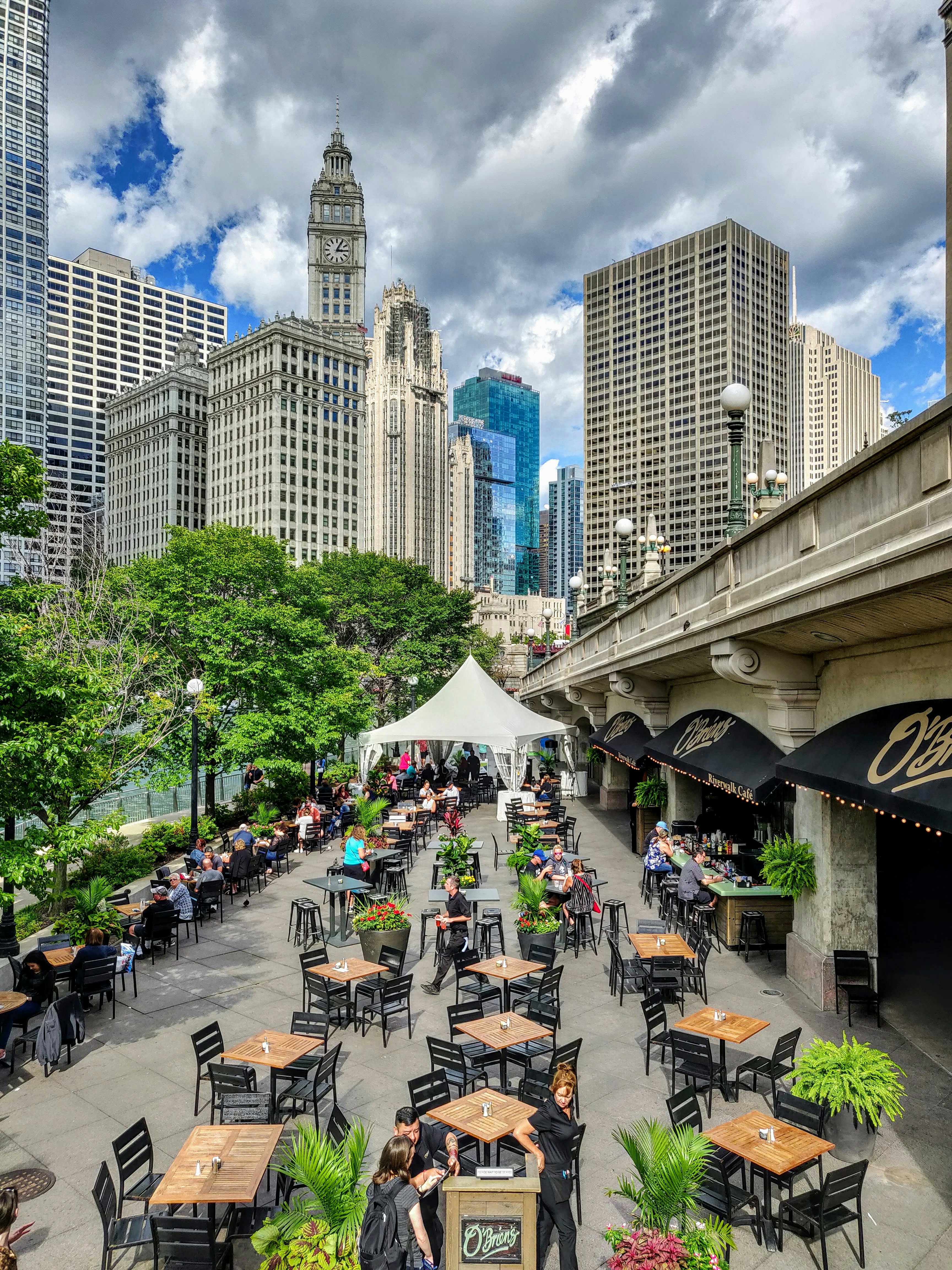 people sitting on chairs near green trees and buildings during daytime