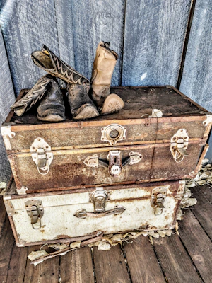 A rustic wooden storage trunk with metal accents, placed at the foot of a bed filled with blankets.