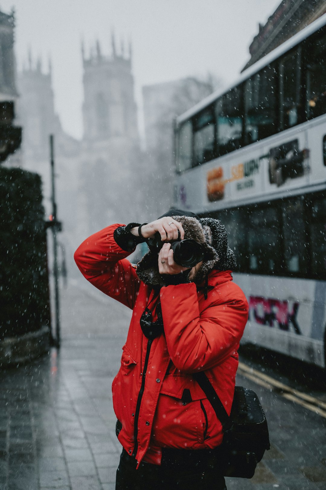 person in red jacket holding black dslr camera