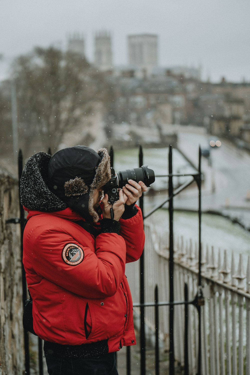 woman in red jacket holding black dslr camera