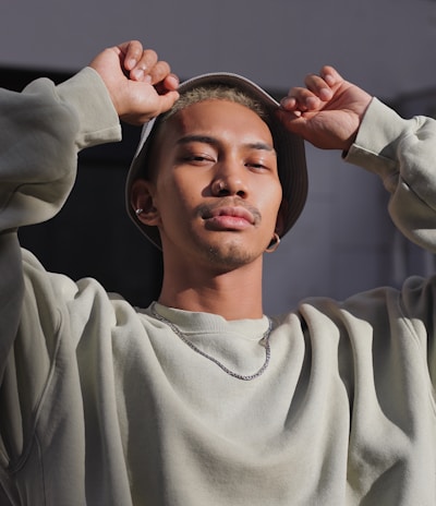 man in white sweater holding round mirror