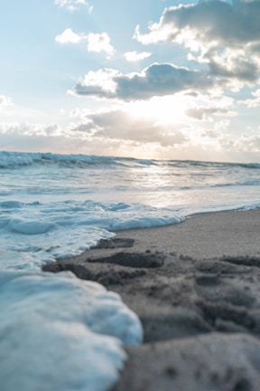 ocean waves crashing on shore under cloudy sky during daytime