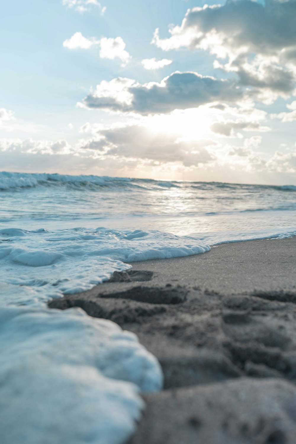 ocean waves crashing on shore under cloudy sky during daytime